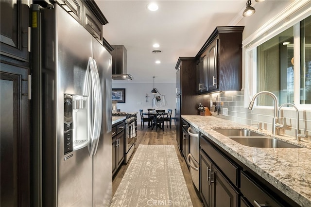 kitchen with a sink, tasteful backsplash, stainless steel appliances, wall chimney exhaust hood, and dark brown cabinets