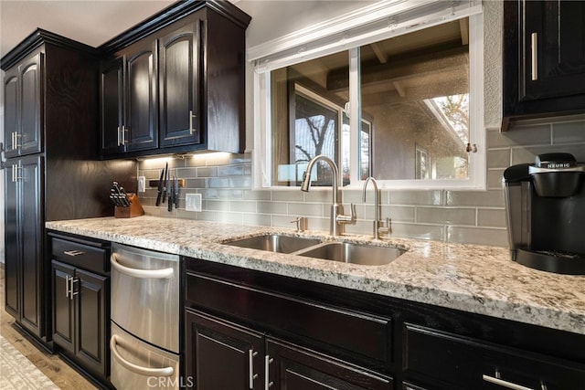 kitchen with a sink, decorative backsplash, light stone countertops, and light wood-style floors