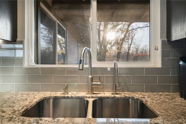 room details featuring light stone counters, backsplash, and a sink