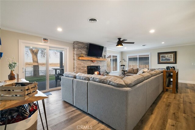 living area with a healthy amount of sunlight, crown molding, and dark wood-style flooring