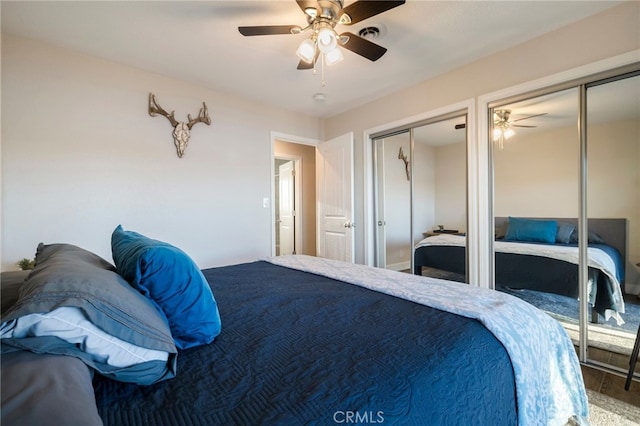 bedroom with wood finished floors, a ceiling fan, multiple closets, and visible vents