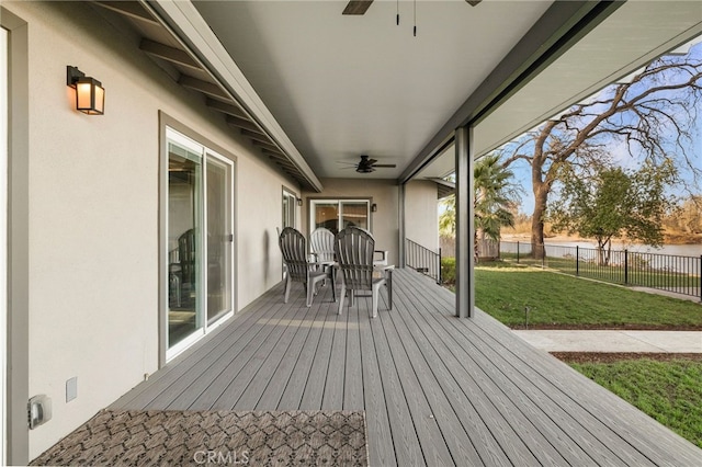 wooden terrace featuring fence, a ceiling fan, and a lawn