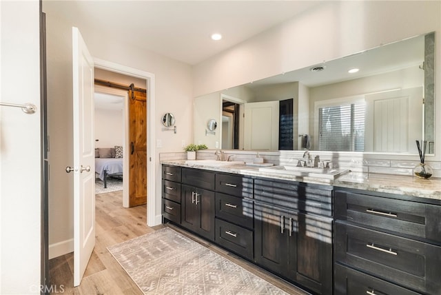 full bath featuring a sink, ensuite bath, wood finished floors, and double vanity