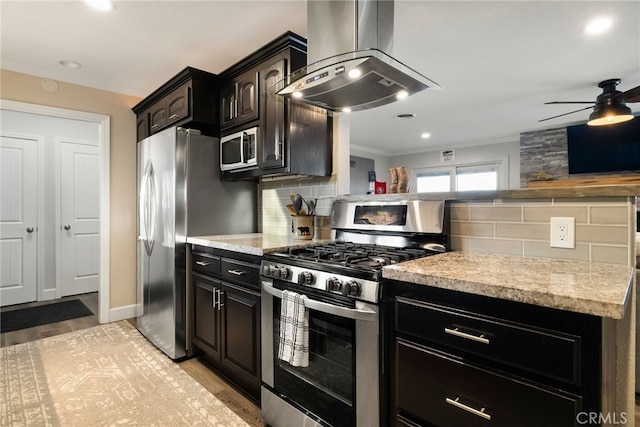 kitchen with light wood finished floors, crown molding, decorative backsplash, stainless steel appliances, and wall chimney exhaust hood