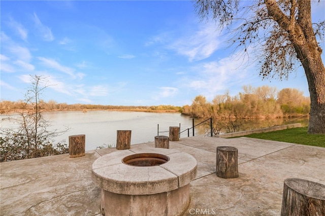 view of patio featuring a water view, a fire pit, and a boat dock