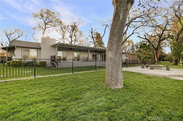 exterior space featuring a patio area, stucco siding, a lawn, and a fenced front yard