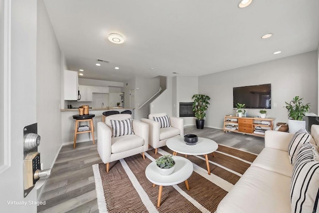 living area with recessed lighting, visible vents, light wood finished floors, and baseboards