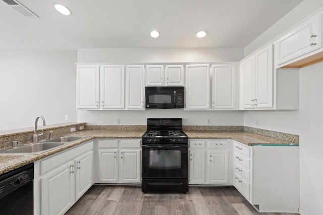 kitchen featuring visible vents, black appliances, light wood-style floors, white cabinetry, and a sink