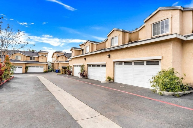 exterior space with a garage, a residential view, and stucco siding