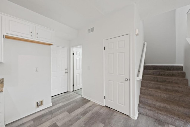 interior space with stairway, baseboards, light wood-type flooring, and visible vents