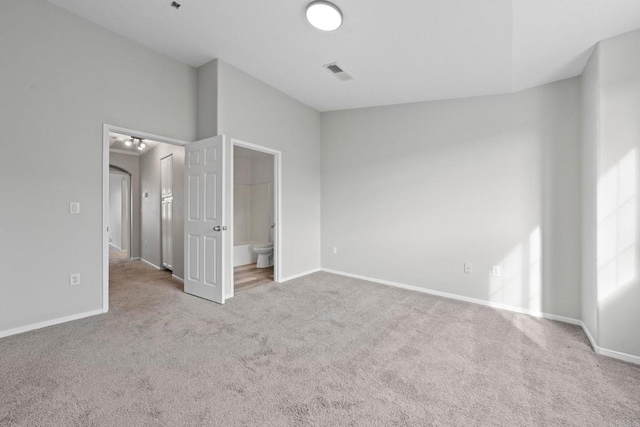 unfurnished bedroom featuring visible vents, baseboards, ensuite bath, and carpet flooring