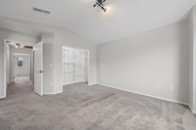 unfurnished bedroom with visible vents, baseboards, carpet, and vaulted ceiling