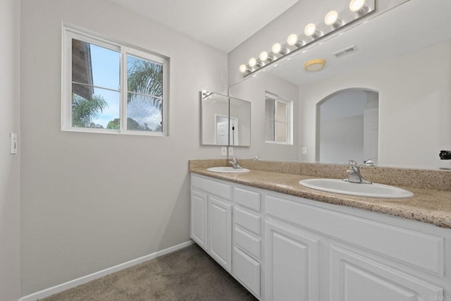 bathroom with double vanity, visible vents, baseboards, and a sink