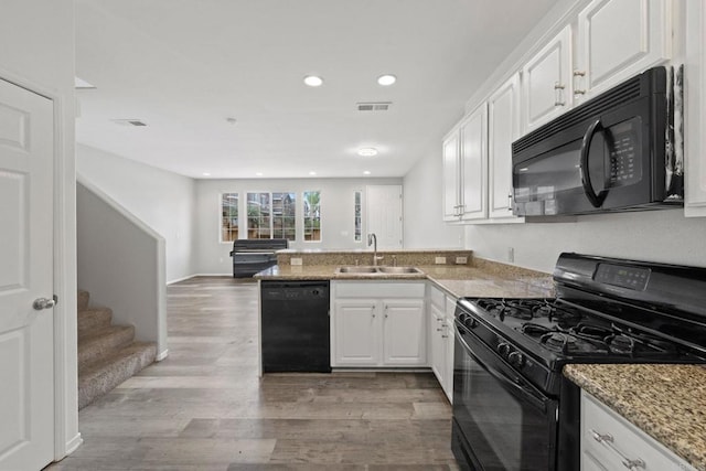 kitchen featuring black appliances, white cabinets, visible vents, and a sink