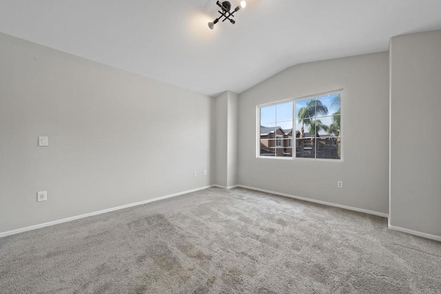 unfurnished room featuring baseboards, lofted ceiling, and carpet floors