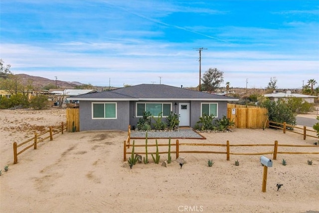 single story home with fence, a mountain view, driveway, and stucco siding