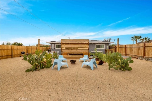 back of house featuring solar panels, a patio, a fenced backyard, and an outdoor fire pit