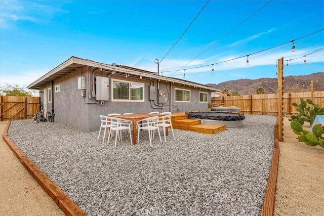 rear view of property featuring outdoor dining space, a fenced backyard, stucco siding, a patio area, and a mountain view