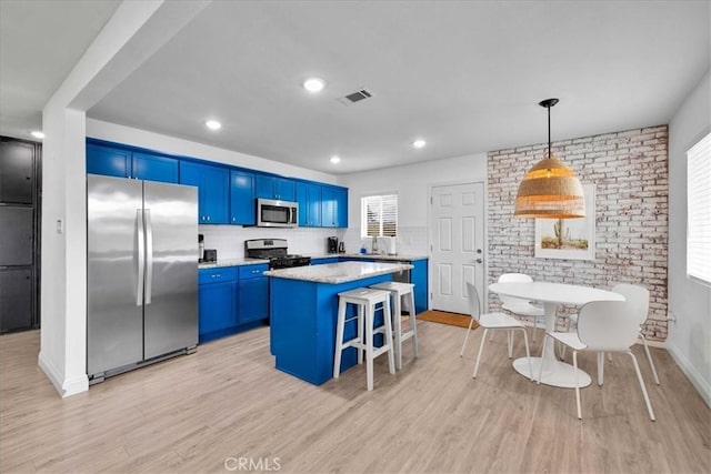 kitchen featuring blue cabinetry, a kitchen island, a breakfast bar area, light wood-type flooring, and stainless steel appliances