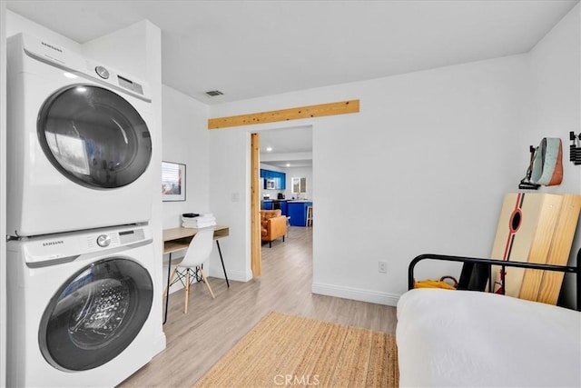 laundry room with visible vents, baseboards, light wood-type flooring, laundry area, and stacked washer and clothes dryer