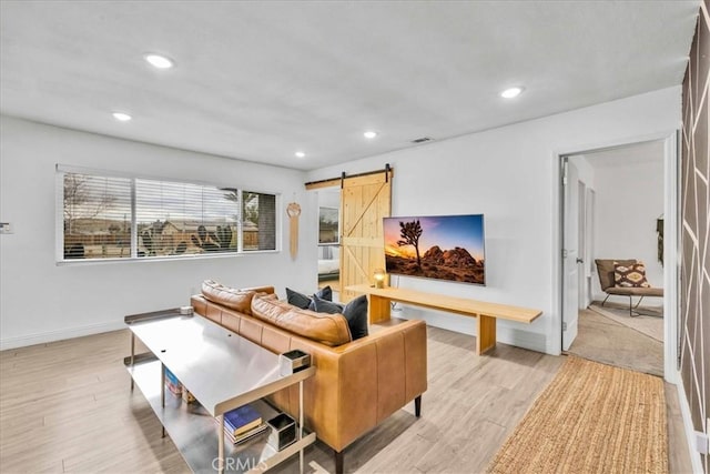 living area with visible vents, recessed lighting, a barn door, light wood-style floors, and baseboards