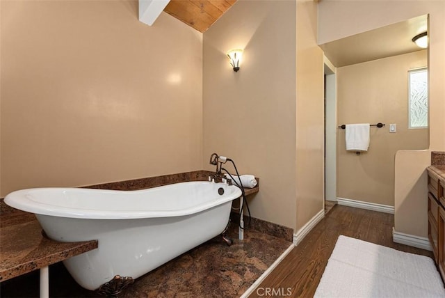 full bathroom featuring baseboards, a freestanding bath, wood finished floors, and vaulted ceiling