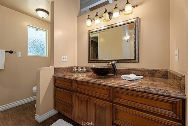 bathroom featuring vanity, toilet, wood finished floors, and baseboards