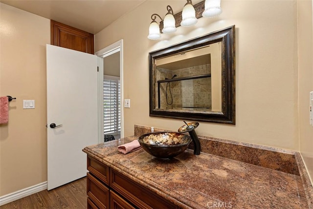 full bath with vanity, wood finished floors, baseboards, and tiled shower