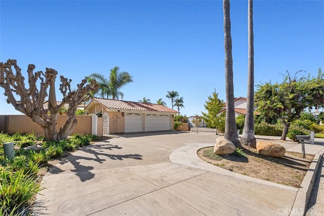 view of front of house with fence, a tiled roof, stucco siding, driveway, and a gate