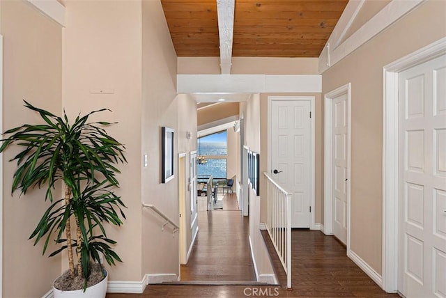 hallway featuring wooden ceiling, baseboards, dark wood-style flooring, and vaulted ceiling with beams