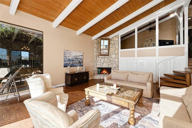 living area with beamed ceiling, wood ceiling, a fireplace, wood finished floors, and a ceiling fan