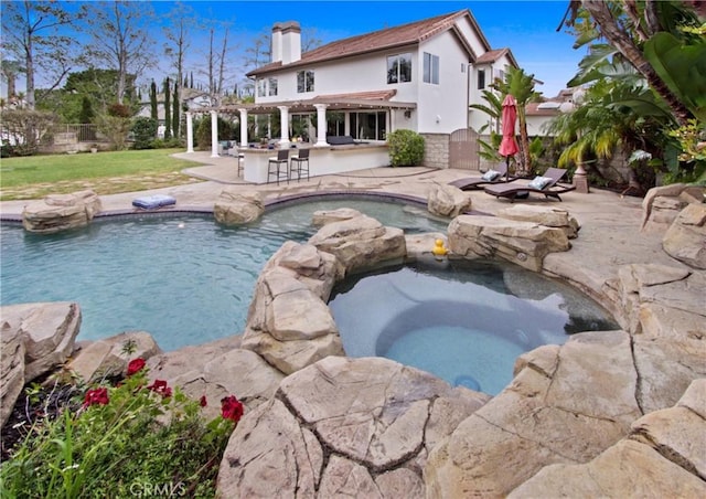 view of pool with a patio, fence, a pergola, and a pool with connected hot tub