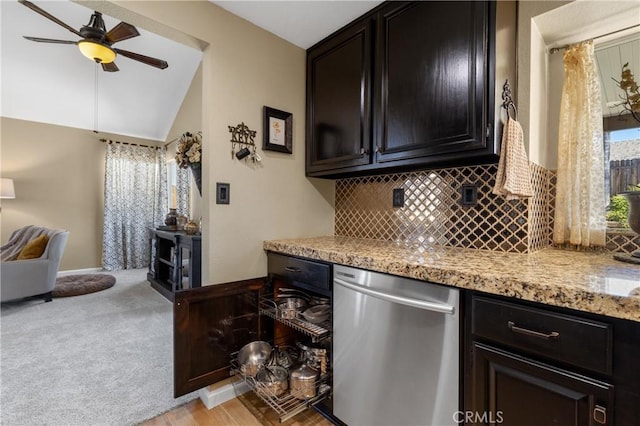 kitchen featuring light stone counters, a ceiling fan, decorative backsplash, stainless steel dishwasher, and light colored carpet