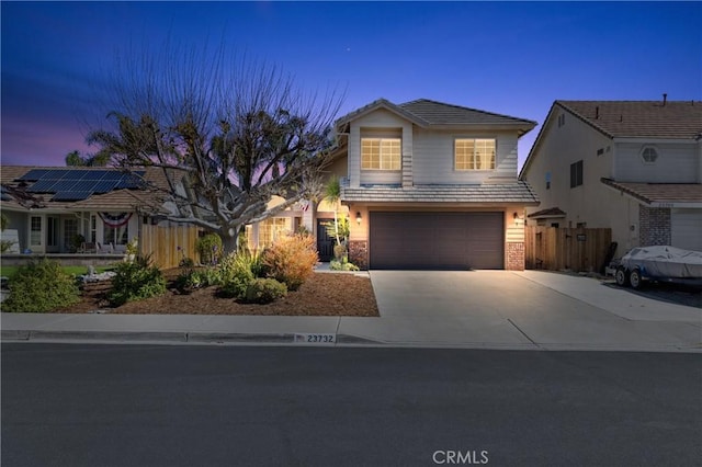 traditional-style home with a tiled roof, a garage, driveway, and fence