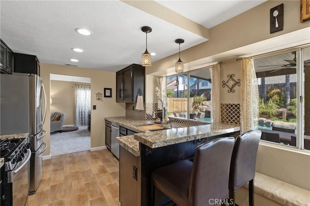 kitchen with a peninsula, stainless steel appliances, a wealth of natural light, and a sink