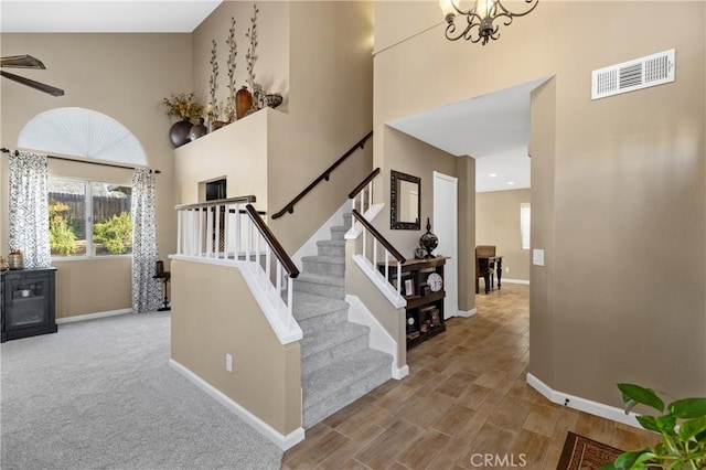 stairway featuring a high ceiling, baseboards, and visible vents