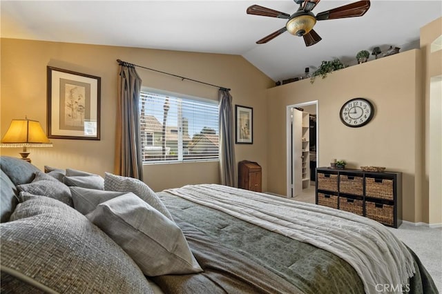 carpeted bedroom with a walk in closet, lofted ceiling, baseboards, and ceiling fan