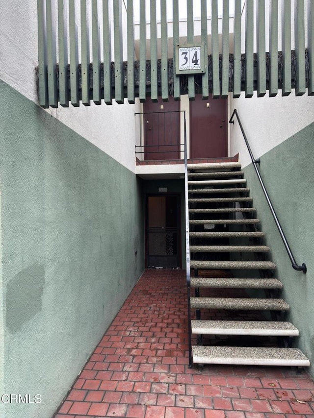 staircase featuring a high ceiling and brick floor