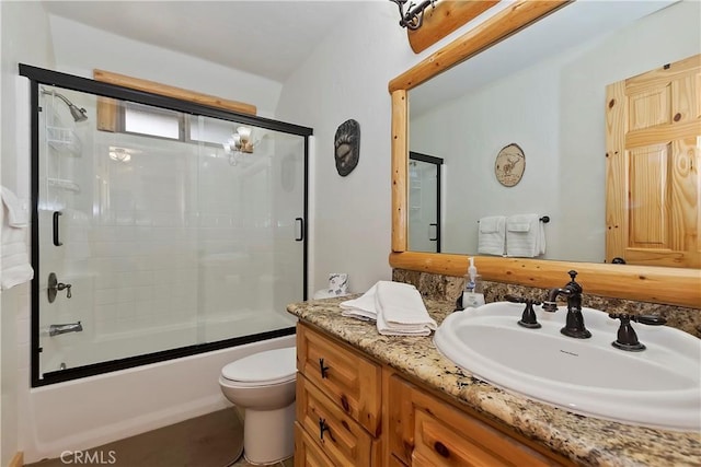 full bathroom with combined bath / shower with glass door, toilet, and vanity