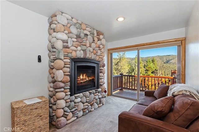 living room with a stone fireplace and carpet floors