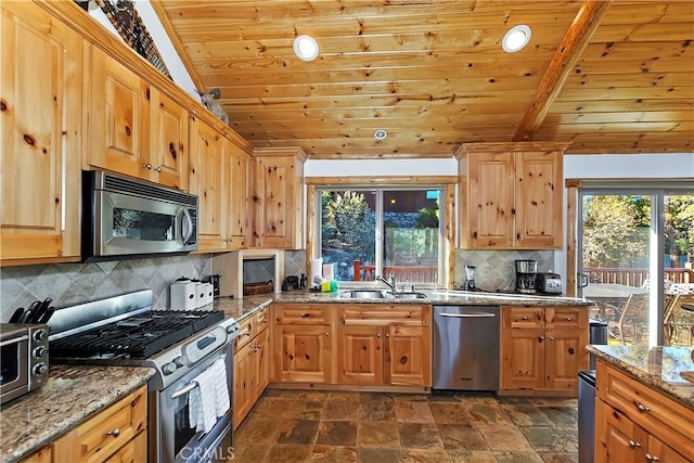 kitchen featuring a healthy amount of sunlight, lofted ceiling with beams, a sink, appliances with stainless steel finishes, and wooden ceiling