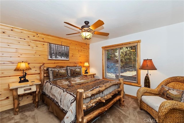 bedroom with a ceiling fan, wooden walls, and carpet flooring