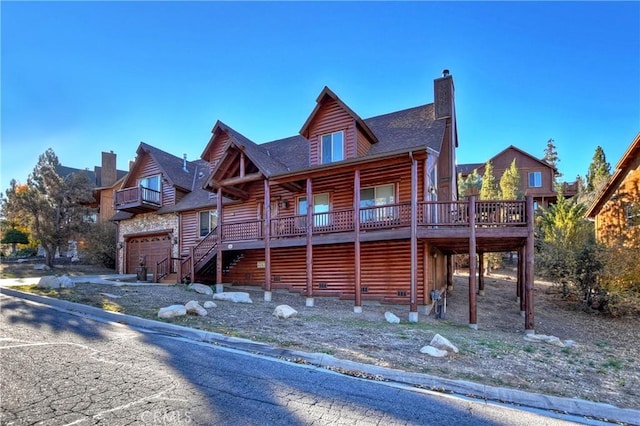 cabin featuring stairway, a chimney, log veneer siding, and roof with shingles