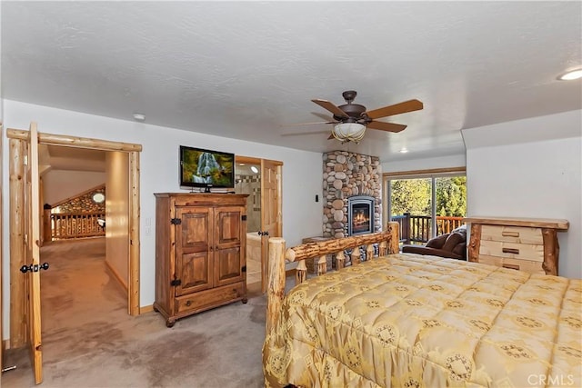 bedroom featuring light carpet, a stone fireplace, a textured ceiling, a ceiling fan, and access to outside