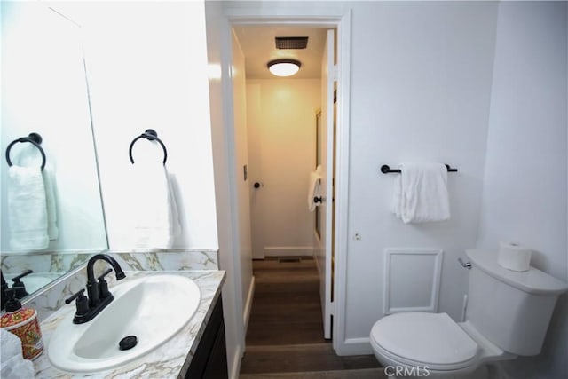 bathroom with visible vents, baseboards, toilet, wood finished floors, and vanity