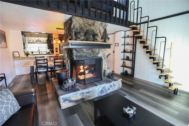 living area with a high end fireplace, wood walls, stairs, and wood finished floors