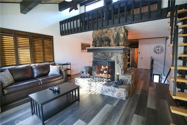 living area featuring a towering ceiling, baseboards, wood finished floors, and a fireplace