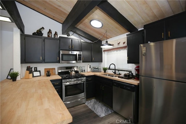 kitchen with dark cabinetry, butcher block counters, appliances with stainless steel finishes, and a sink