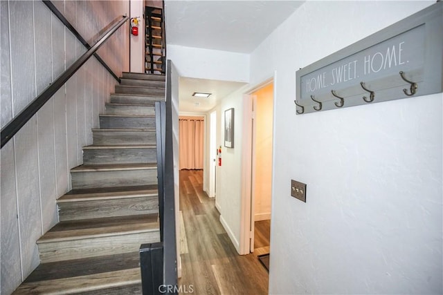 staircase featuring wooden walls and wood finished floors