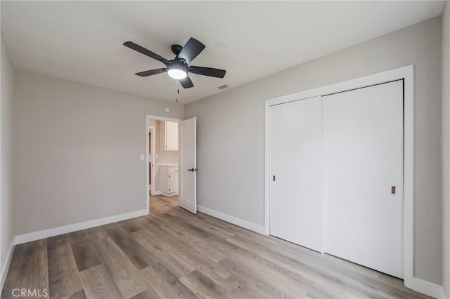 unfurnished bedroom featuring wood finished floors, visible vents, baseboards, ceiling fan, and a closet